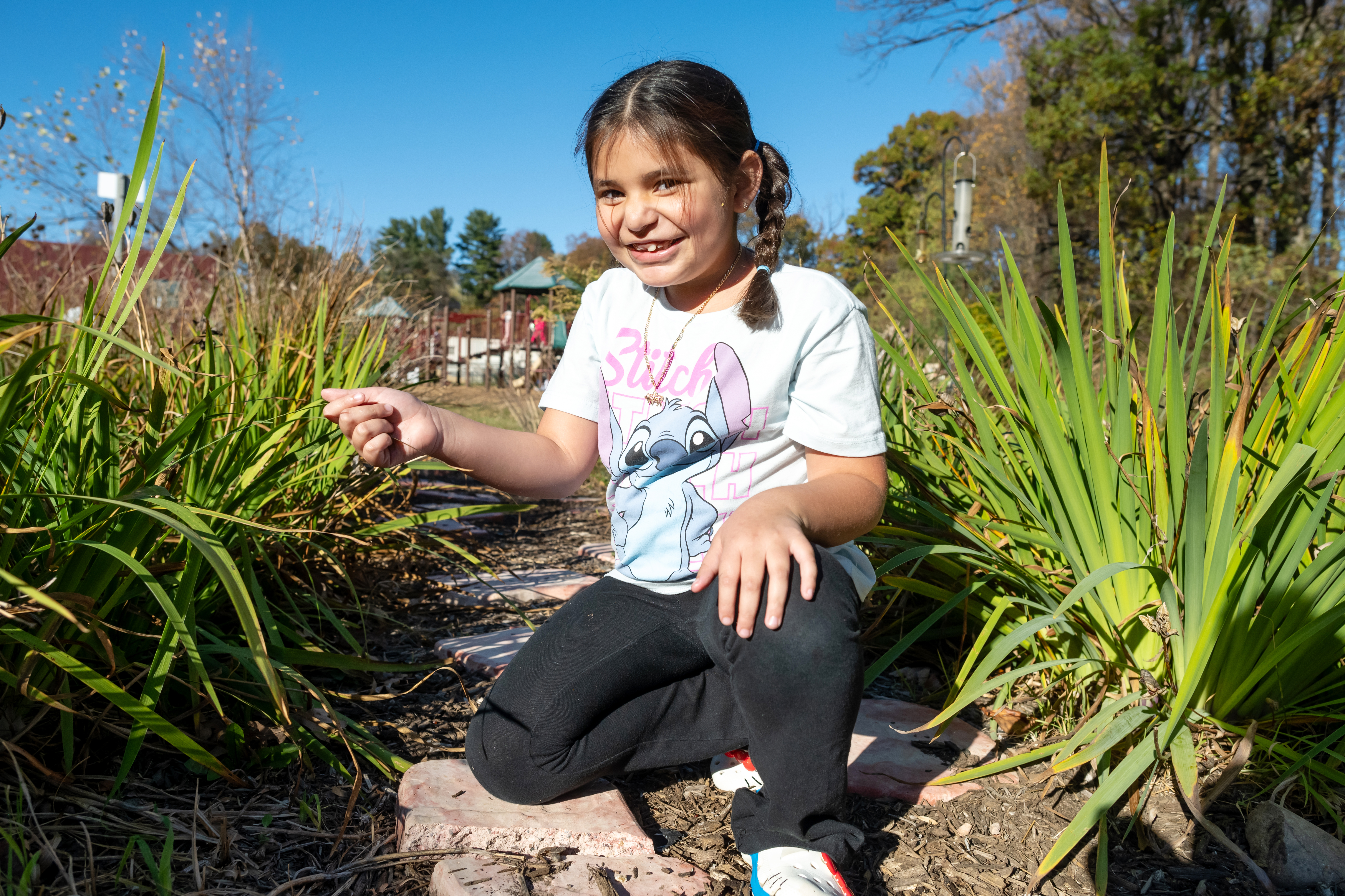 Female student kneeling while exploring the butterfly garden