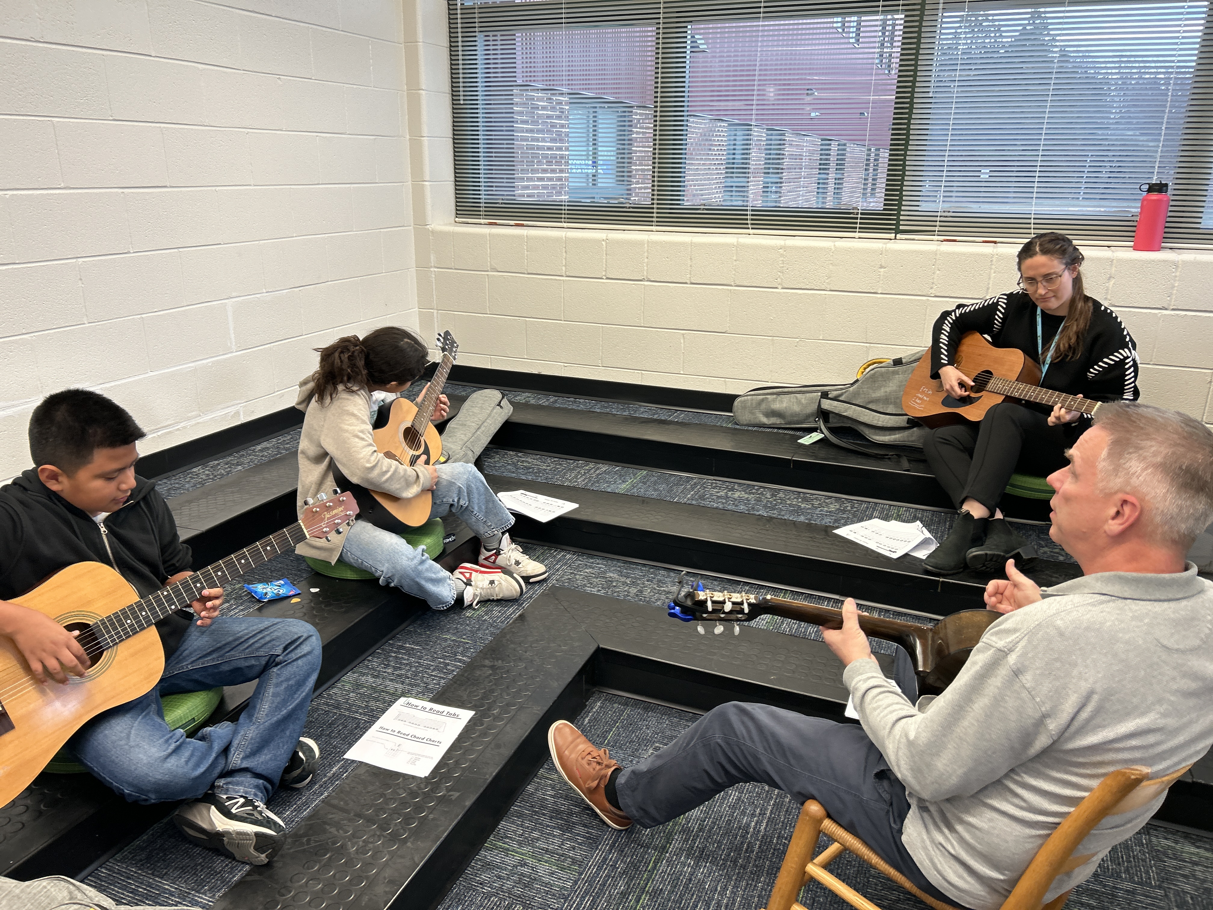 Mr. Newlon is teaching guitar to students and staff in the library after school.